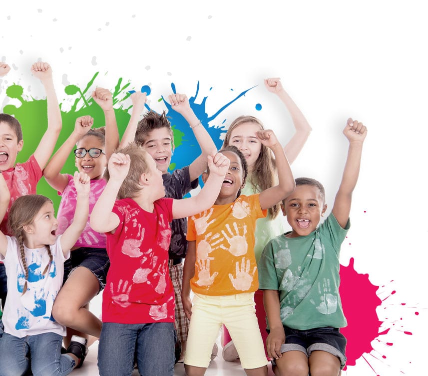 A diverse group of smiling children wearing colorful, paint-splattered shirts raise their arms in celebration in front of a white background with colorful paint splashes.